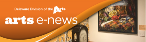 Delaware Division of the Arts arts e-news banner over over a photo of where two walls meet in the corner. One wall is white with a painting hanging on it, and the other wall is covered in decorative, yellow wallpaper with an antique, wooden desk clock sitting in front of it on a desk