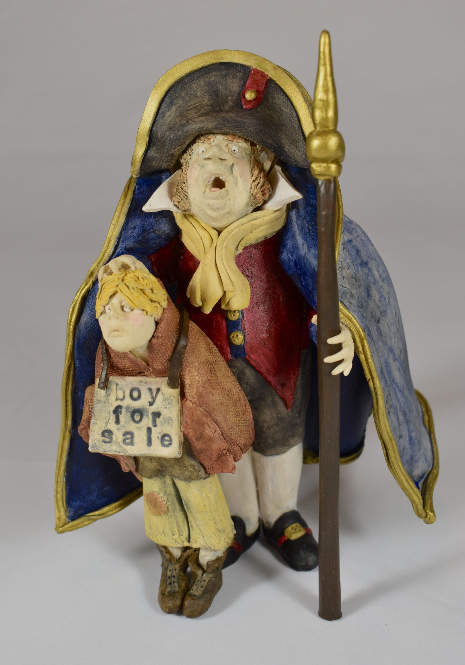 A clay figure of a man holding a boy with a sign around his neck