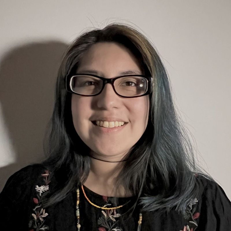 A woman wearing glasses amd a black shirt, with many beaded necklaces on.