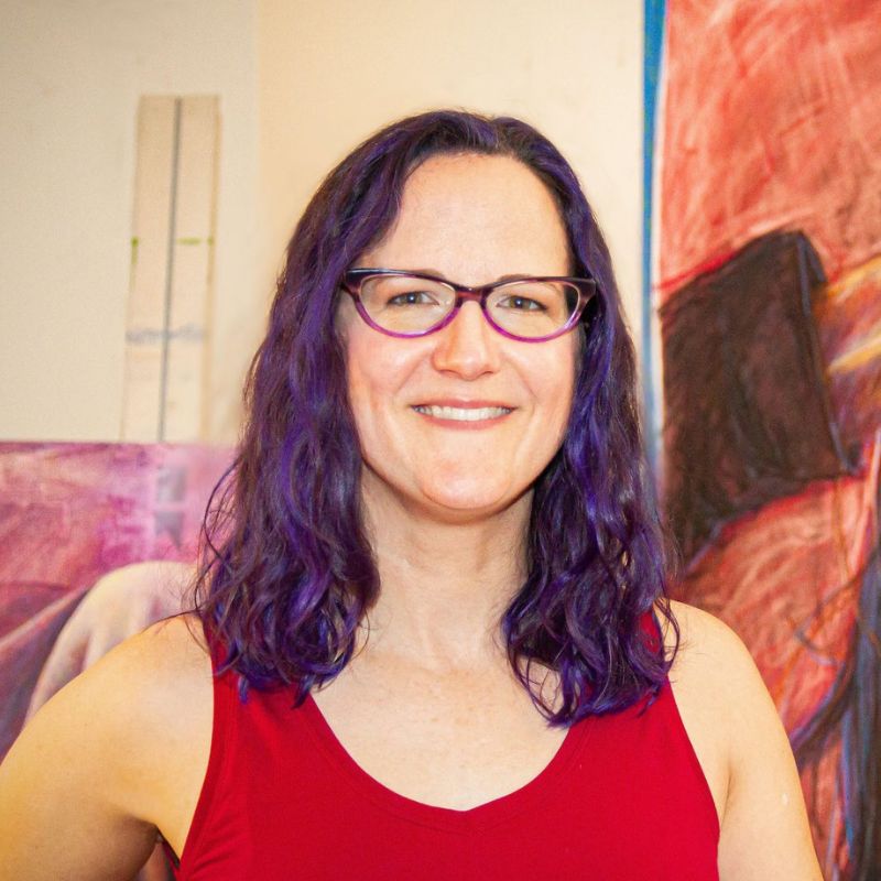 A white woman in a red shirt, next to a large painting that looks like her.