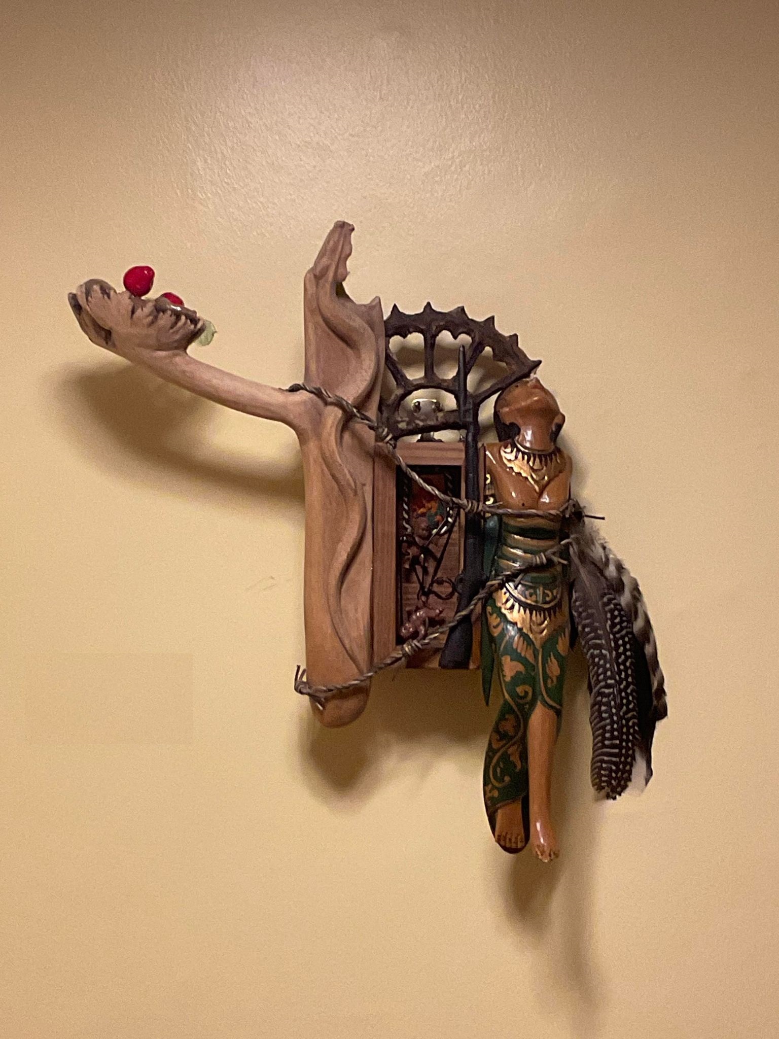 A wood sculpture with feathers, leather, and various objects.