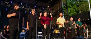 Photo of several people singing into microphones