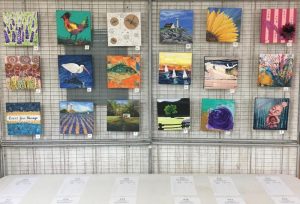 a variety of artworks that are all 8x8 in size hanging on a wall.