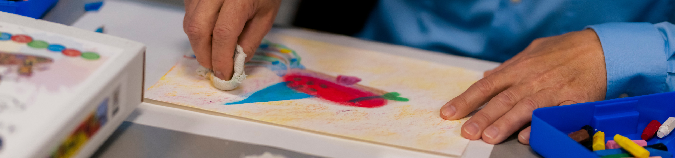 hands making art with multiple colors on a piece of paper