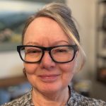 Headshot of a woman in black glasses, indoors.