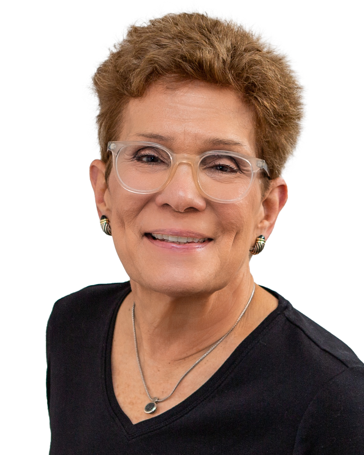 Headshot of a smiling person with short reddish-brown hair wearing clear-framed glasses, earrings, and a necklace, dressed in a black top against a white background.