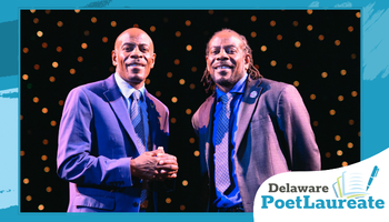 Promotional banner featuring two men in suits standing together on a stage, smiling toward the camera, with warm circular lights in the dark background. A teal graphic frame surrounds the photo, and a badge in the lower right reads “Delaware Poet Laureate” with an open-book icon.