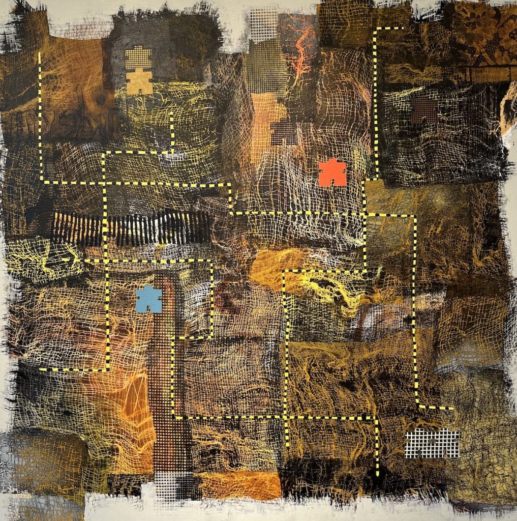 Abstract mixed-media work in earthy browns, black, ochre, and orange with visible mesh-like textures and stitched-looking dotted yellow lines forming irregular pathways. Small puzzle-piece shapes in blue, orange, and white punctuate the surface, adding contrast to the rough, organic patchwork background.