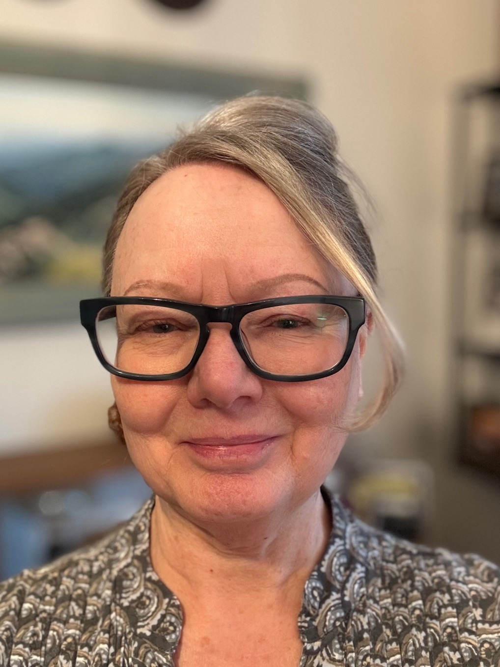 Headshot of a woman in black glasses, indoors.