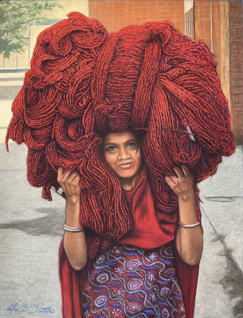 Realistic photo of a young woman standing outdoors while carrying an enormous bundle of thick red yarn or rope on her head and shoulders. She wears a red top and a patterned skirt in blue and red tones, and her direct gaze and faint smile contrast with the visual weight of the vivid mass above her.