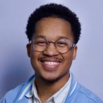 A young black man with black hair and glasses.