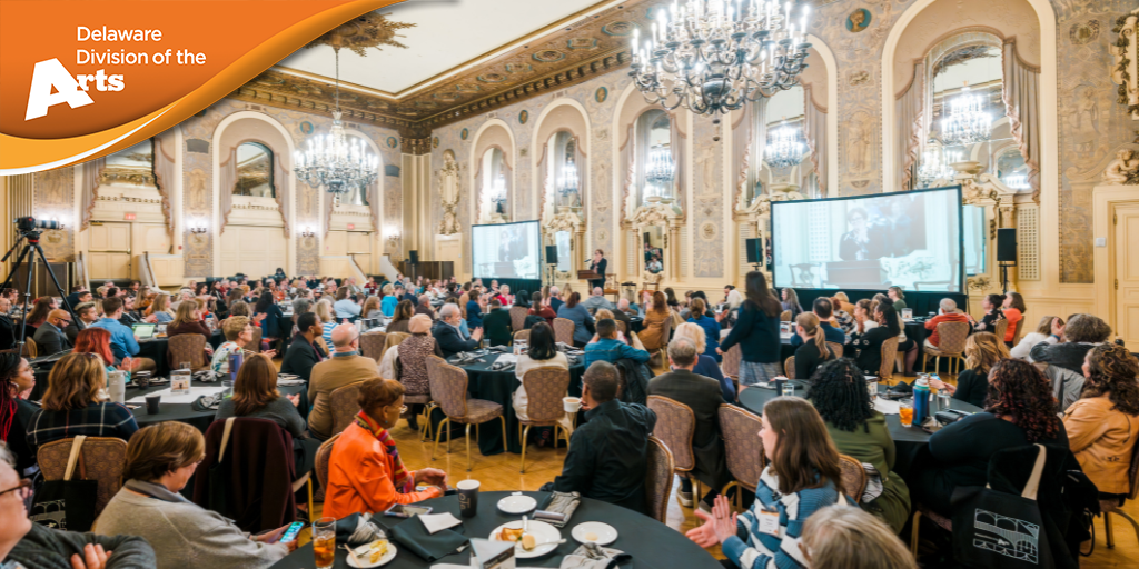 a full ballroom listens to a person on the stage