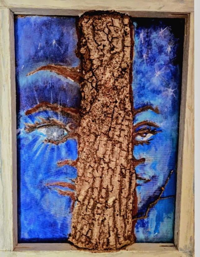 Framed mixed-media artwork showing two blue-toned faces divided by a vertical tree trunk made of textured bark. The composition suggests separation and connection, with each half of the face peering out from opposite sides of the trunk against a vivid blue background.
