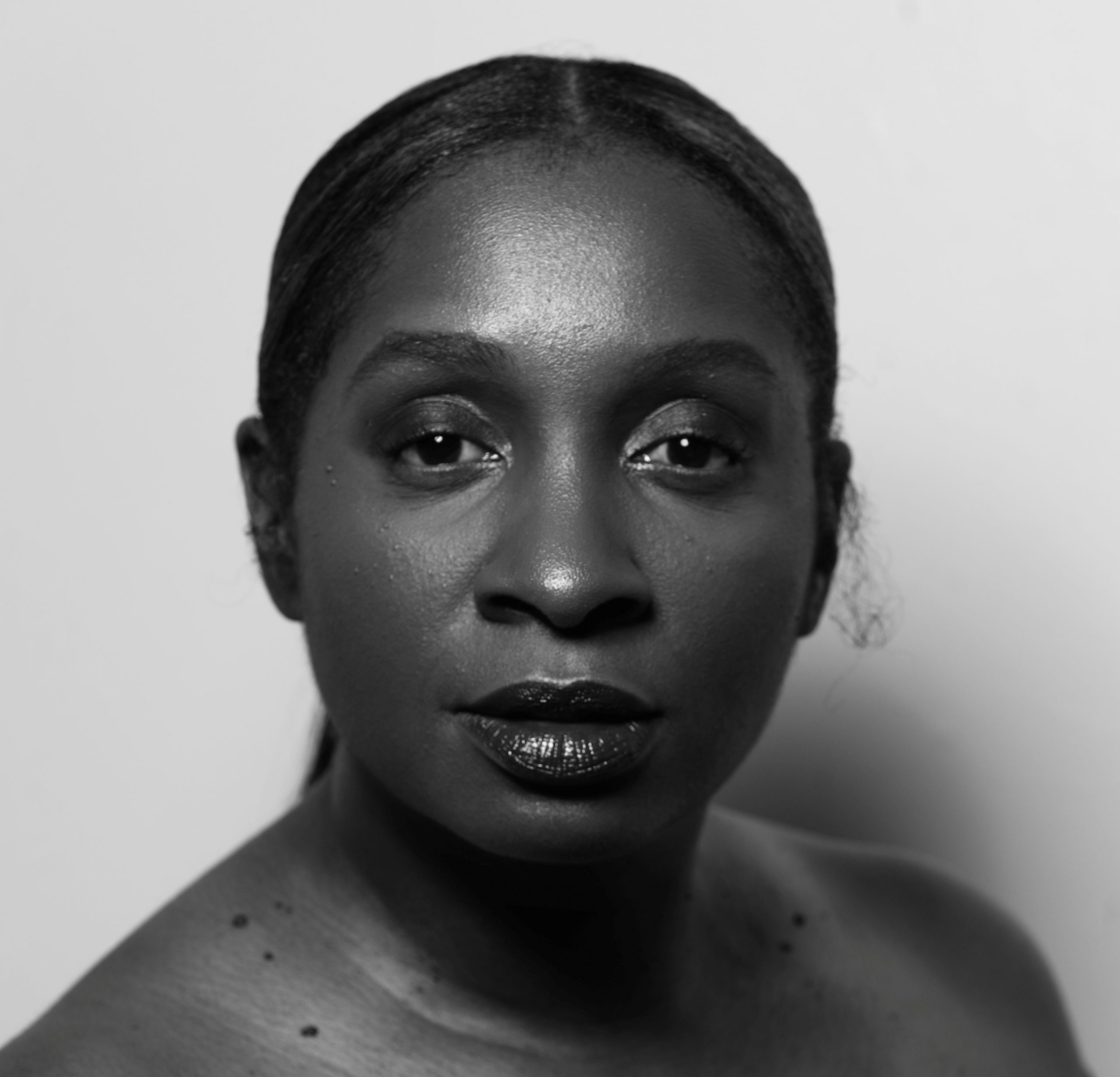 a young african american woman stares directly at the camera in a black and white photo