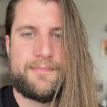 A white man with long, light brown hair and a beard.