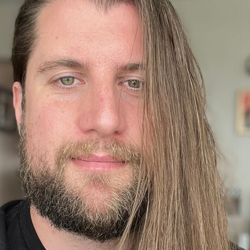 A white man with long, light brown hair and a beard.